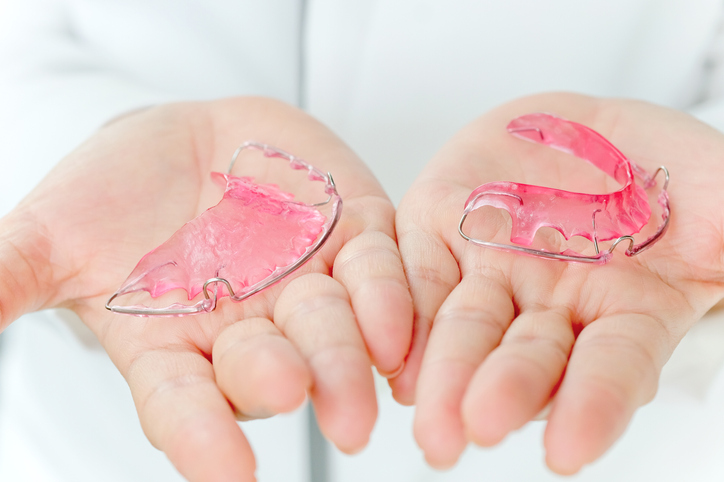 dwa różowe aparaty ortodontyczne na dłoniach