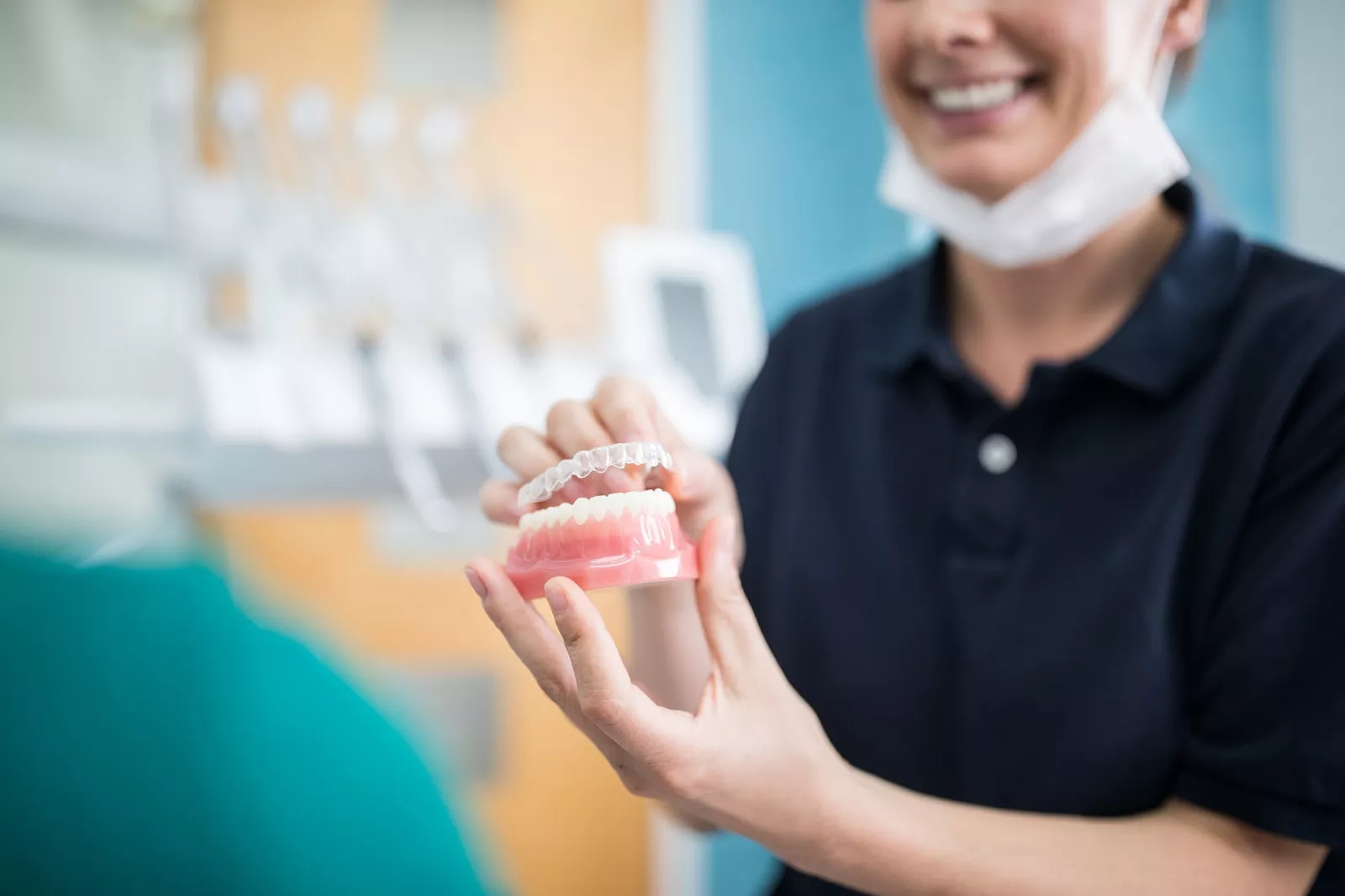 Uśmiechnięta kobieta z implantem zębowym w rękach